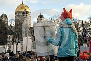 Young girl in fox mask hold poster in her hand and look at the church