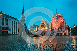 Riga, Latvia. Scenic Town Hall Square With St. Peter's Church, Schwabe House, House Of Blackheads During Night Rain