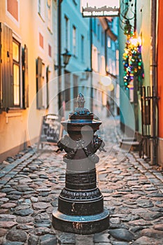 Riga, Latvia. Small Column Pillar Shaft Stake Pile With Lions Heads At Torna Street In Old Town. Narrow Street In photo