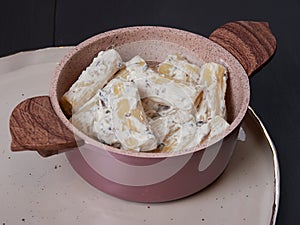 Rigatoni with cream, gorgonzola and olives, on a dark brown board photo