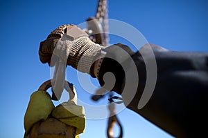 Rigger high risk worker wearing heavy duty glove and clipping a crane hook into lifting lug prior to lift