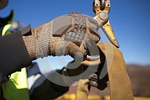 Rigger high risk worker wearing heavy duty glove and clipping a crane hook into yellow three tones lifting sling prior to lift