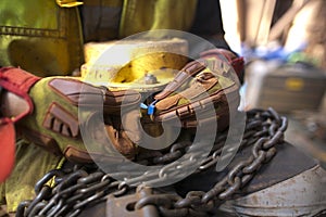 Rigger wearing a glove inspecting using blue plastic tag and tagging a heavy duty 2 tone chain hoist lifting equipment