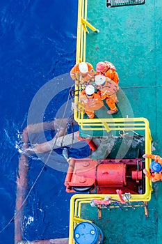 Riggers working on anchor handling on a construction wok barge at offshore Terengganu oil field during sunrise