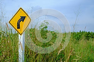 Right bend traffic warning sign on feather grass field