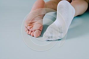 right foot in dirty sock, left foot without socks. on gray background