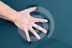 Right male hand pushing down back sand on a beach