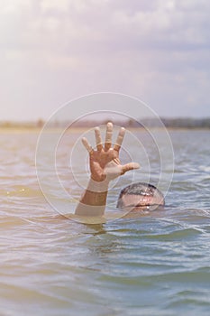 Right man`s hand gives a signal for help out of the water