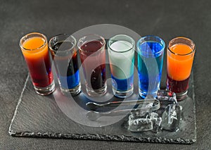 Right side view on a six different colored shot drinks, lined up