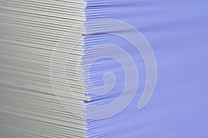 A right vertical corner of a stack of many sheets of thick paper or cardstock. One of the sides is blue. Book publishing or