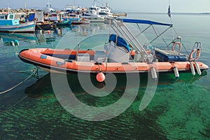 Rigid-hulled inflatable boat floating on calm blue transparent sea water of Greek Kos island