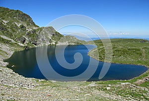 Rila mountains in Bulgaria, deep blue lakes and gray rock summit during the sunny day with clear blue sky