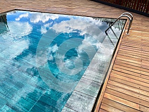 Rimless pool, with the exterior surrounded by teak wood, deep blue crystal clear water, swimming pool staircase, wellness spa