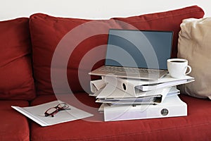 Ring binder, laptop and coffee on a red couch, mandatory home office work during coronavirus outbreak crisis, copy space