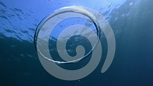 Ring bubble and sun underwater in blue ocean. Water texture
