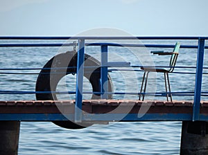 Ring-buoy and chair on the river pier. It`s all we need, I think