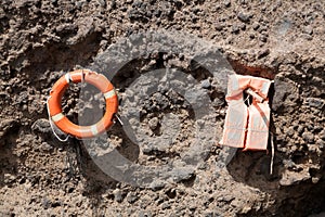 A Ring buoy and life jacket hang on a rock