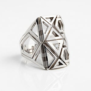 Ring is displayed on a smooth reflective white surface emphasizing its