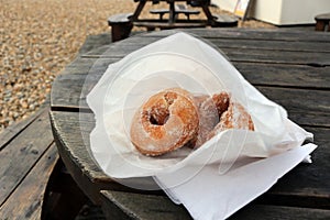ring doughnuts in a paper bag on a table at the beach