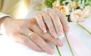 Ring & hands over white and flowers, wedding day