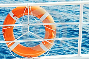 Ring life buoy on boat. Obligatory ship equipment. Orange lifesaver on the deck of a cruise ship.