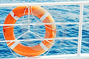 Ring life buoy on boat. Obligatory ship equipment. Orange lifesaver on the deck of a cruise ship
