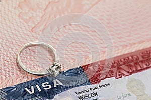 A ring with a precious stone on the background of a US visa as a symbol of engagement