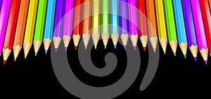 Ring of rainbow colored pencils creating a circle shape isolated over black background.