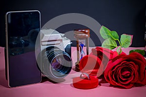 Ring in red box, beautiful red rose, phone, camera and hourglass