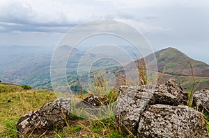 The Ring Road in Cameroon, Africa with soft hills in background and large rocks in foreground on overcast day