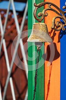 Ringing old bell on the colorful wall. Vintage metal rusty bell. Brass ship\'s bells with ropes hanging on wooden wall
