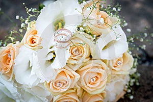 Rings on a wedding bouquet of white flowers and peach roses