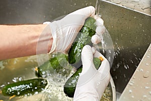 Rinsing cucumbers under tap water.