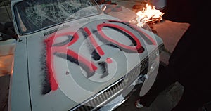 Riot Fire. Protest. Revolution girl in post-apocalypse world. Crushed burned car