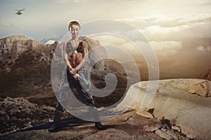 Riot girl on a rocky ledge with a gun