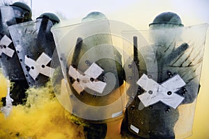 Riot police forming a line carrying perspex shields and wearing helmets photo