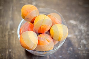 Ripe appetizing apricots in a bowl on a wooden table