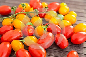 Ripe appetizing yellow and red cherry tomatoes on wooden table