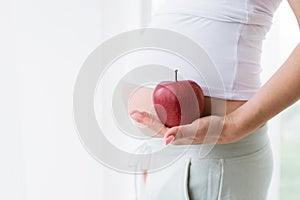 Ripe apple in hands of pregnant woman