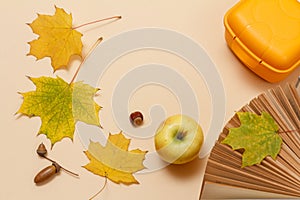 Ripe apple, lunchbox and dry leaves on a beige background, Top view