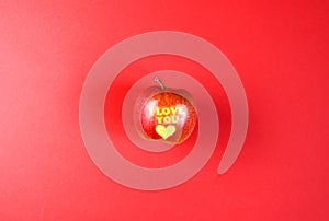 Apple with words I LOVE YOU on red background