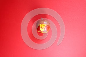 Apple with words I LOVE YOU on red background