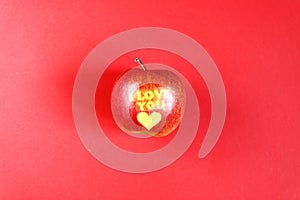 Apple with words I LOVE YOU on red background