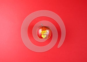 Apple with words I LOVE YOU on red background