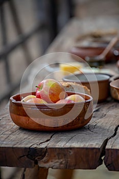 Ripe apples in a ceramic bowl close-up, pottery on a wooden table, medieval lifestyle, still life