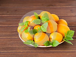 ripe apricots on a plate on a wooden table.