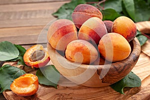 Ripe apricots in a wooden bowl on the background of not painted boards