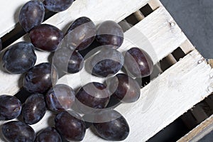 Ripe aromatic plums. Located on a wooden box, knocked out of the boards.