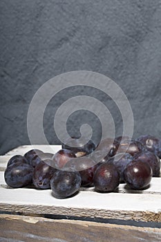 Ripe aromatic plums. Located on a wooden box, knocked out of the boards.