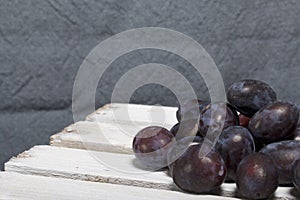 Ripe aromatic plums. Located on a wooden box, knocked out of the boards.